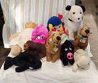 Group shot of entire lot on white cloth showing all stuffed animals and doll