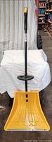 Full view of yellow ergonomic snow shovel with extra lift handle