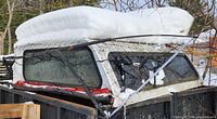 Side view of white truck cap in trailer, rear window and red weather-strip visible