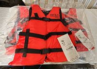 All three life jackets in packaging showing front view, straps, and tags