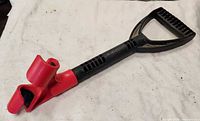 Overall view of black D-grip handle with red clamp