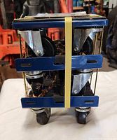 Stacked view of the three blue metal dollies with casters and yellow straps