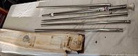 Four stainless pole sections and collar beside original box