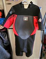 Front view of black and red Body Glove shorty wetsuit on hanger