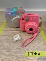 Front view of pink Instax Mini 9 camera, holographic case, close-up lens accessory