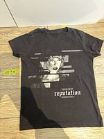 Front view of black Taylor Swift Reputation Stadium Tour t-shirt showing portrait graphic and logo