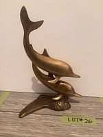 front view of brass two-dolphin sculpture
