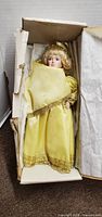 Doll in box with yellow gown and tissue wrap