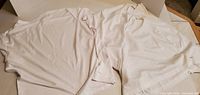 Two white short-sleeve shirts laid flat