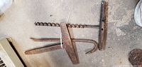All three vintage forged steel tools laid out on floor: auger bit with T-handle, curved pry bar, splitting wedge
