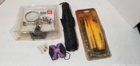 All four items grouped: packaged magnifier, umbrella, Sperry tool, purple X multi-tool