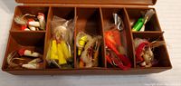 Open brown plastic tackle case showing assorted fishing flies and lures in compartments
