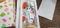 Glass tumbler showing ghost and pumpkin graphics inside foam packaging