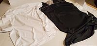 White and black men’s shirts laid flat to show colour, style and condition