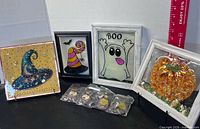 Group shot of four framed epoxy artworks and four packaged earring pairs