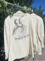 Two jackets on hangers showing embroidered phoenix motif