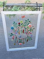 Front view of framed glass suncatcher showing full painted design