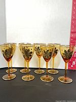 Front row view of all eight glasses showing shape, color, floral design