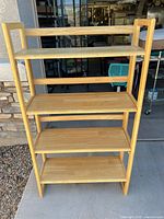 Front view of light natural wood foldable bookcase with four shelves