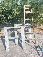 Front view of two wood sawhorses and folded ladder