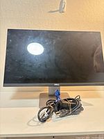 Front view of Dell S2415H monitor on stand with bundled power and VGA cables