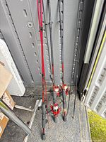 Full view of three red/black Shakespeare spinning rod and reel combos standing upright