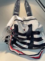 Front view of white and navy striped shoulder bag with handles and adjustable strap