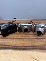 Front view of all three cameras side by side on wooden surface