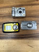 Front view of three digital cameras showing brands and models