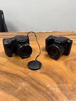 Front view of both Canon SX400 IS cameras with lens cap between