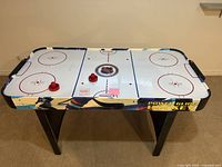 Top view of air hockey table with two paddles and puck on surface