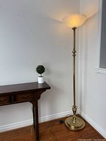 Full view of brass torchiere lamp beside table