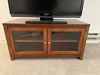 Front view showing glass doors, knobs, wood finish