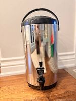 Front view of stainless steel insulated beverage dispenser with spigot and handle