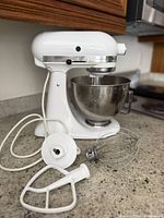 Mixer with bowl and three attachments on countertop