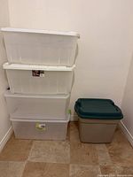 Stack of four clear bins with white lids and one grey bin with green lid