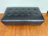 Top view of dark faux leather ottoman showing full rectangular shape and tufting pattern