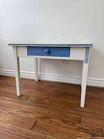 front view of white wood table with blue drawer