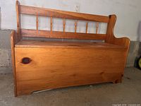 Front view of solid wood bench showing spindle backrest, armrests and slab front panel