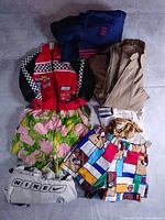 Overview of folded garments including custom shorts, Disney jacket, tan Sears jacket, blue Adidas, white Nike.