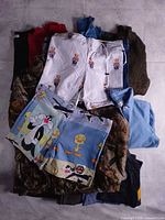 Stacked clothing showing graphic shorts over sweaters and camo jacket