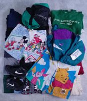 Bundle overview showing assorted sweaters, Reebok windbreaker, Nike boots, vintage Disney shorts