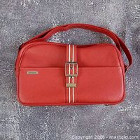 Front view of red leather Samsonite bag showing overall shape, strap, stripes, and buckle