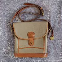 Front view of tan and brown leather Dooney & Bourke crossbody bag with flap and strap visible