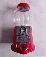 Front view of red cast-metal gumball machine with glass globe and coin mechanism
