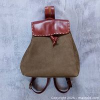 Front view of brown and burgundy leather convertible handbag/backpack showing flap, body, straps