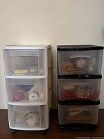 White and black three-drawer plastic carts on wheels with contents visible in drawers