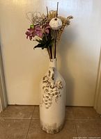 Full view of white decoupage glass bottle with floral arrangement