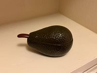 Closed avocado-form bowl with spoon visible, showing overall design and condition