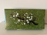 Top view of green rectangular jewelry box with white blossom branch painting